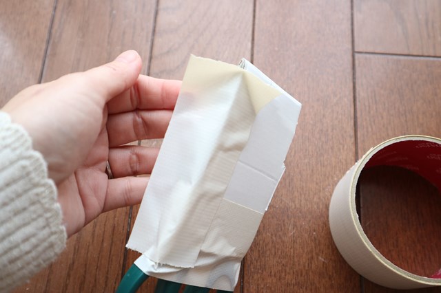 ハサミを包んだ厚紙をテープでとめる